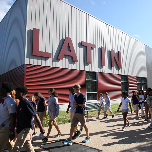 Students walk in front of Latin building on a sunny day.